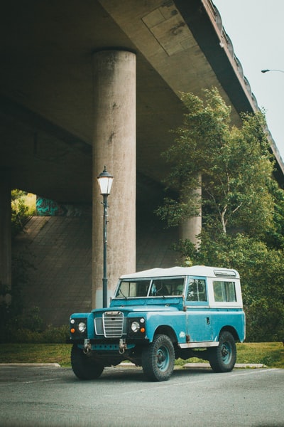 During the day, the blue and white van parked next to the brown cement construction
